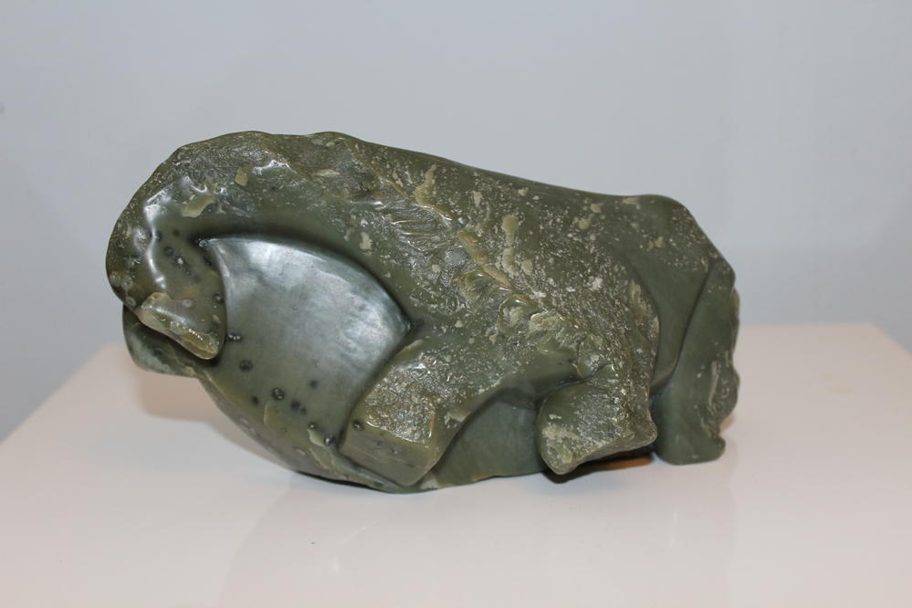Grüne Steinskulptur eines Bären mit gehobenem Kopf und geschwungenem Körper