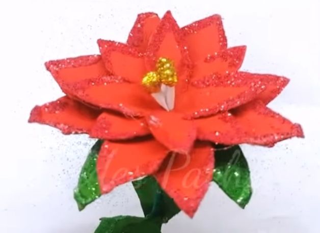 Eine kunstvoll gebastelte rote Weihnachtssternblume mit glitzernden Rändern