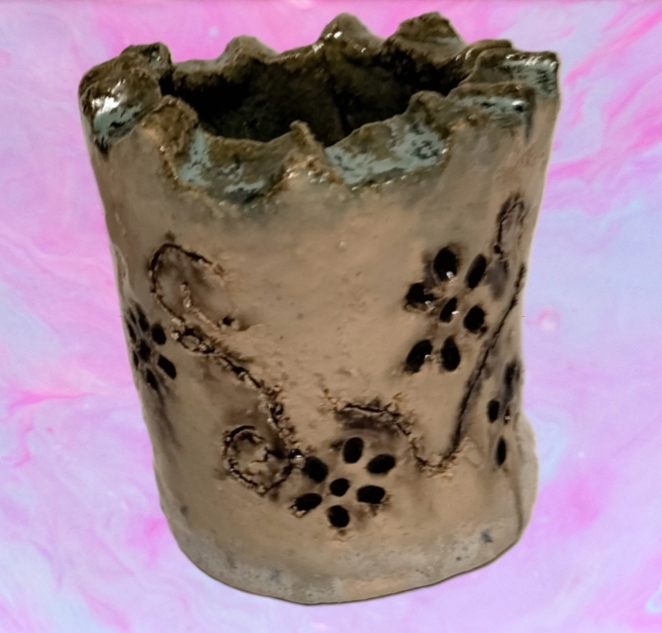 Grau brauner Keramikbecher mit gezacktem Rand und Lochmuster vor Pink