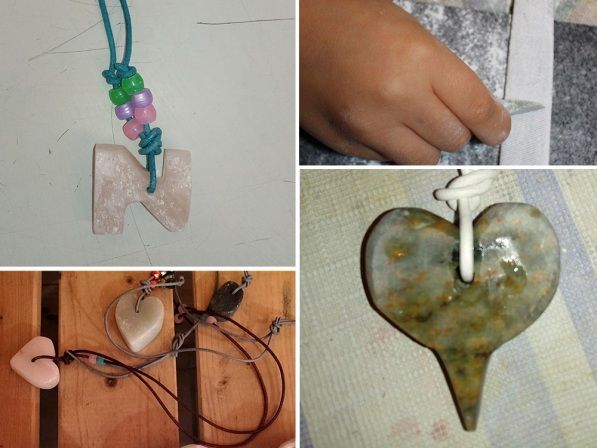 Vier verschiedene Herzstücke und eine Kinderhand beim Schleifen einer Steinanhänger