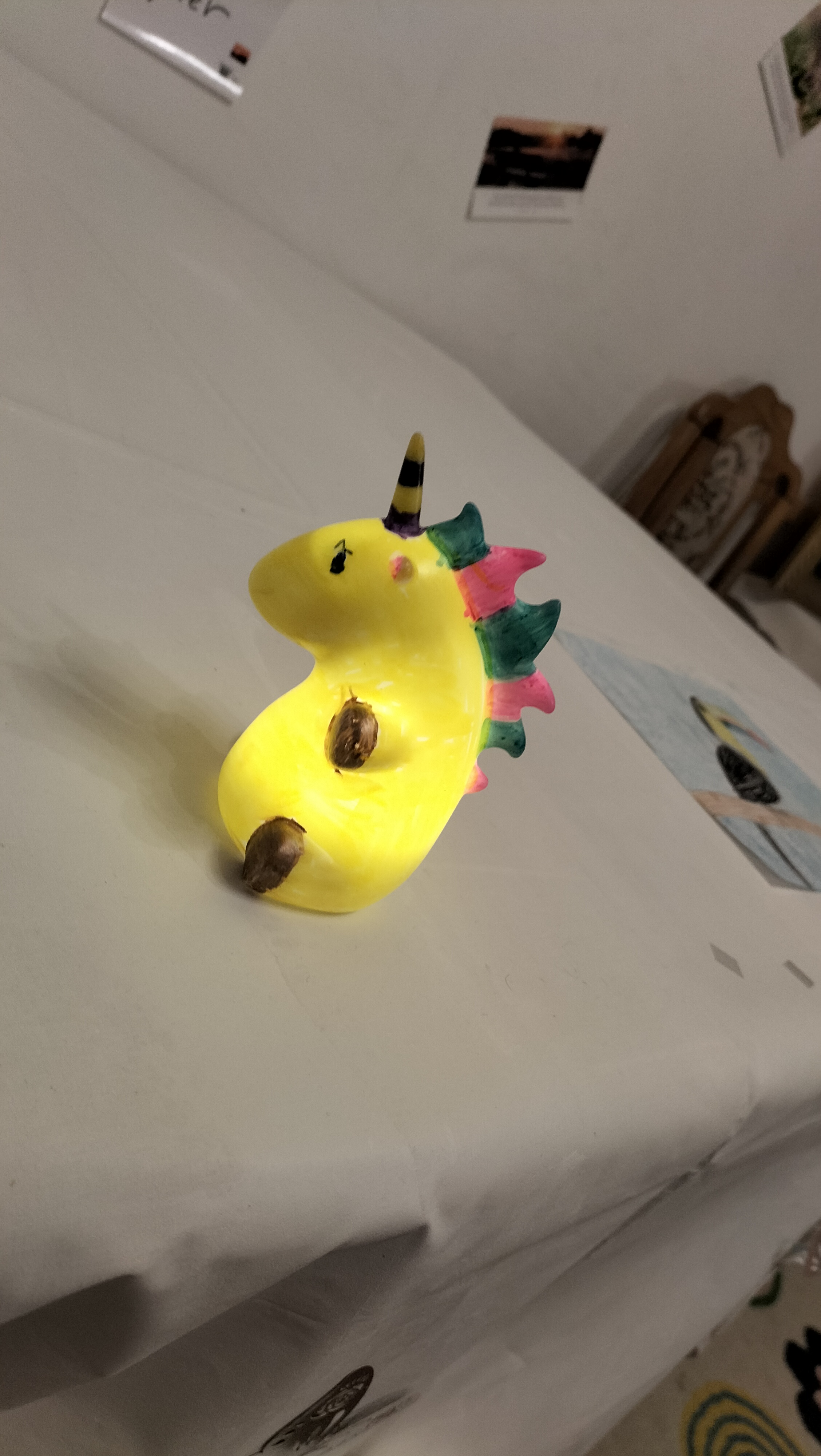 Gelbe handgemachte Einhornfigur mit bunter Mahne und laechelndem Ausdruck